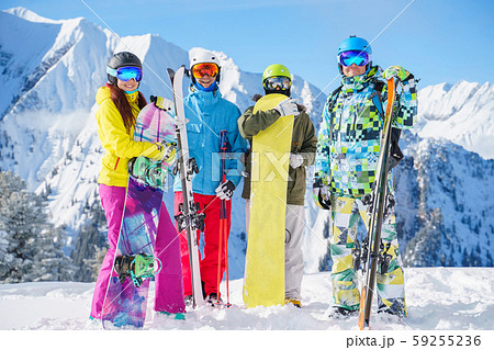 Photo of two sports women and two men with skis and snowboard standing at ski resort Photo of two sports women and two men with skis and snowboard standing at ski resort 59255236
