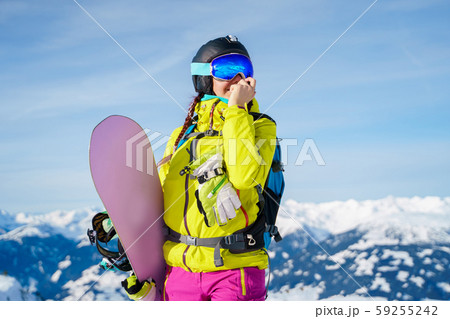 Image of woman in helmet and with snowboard standing at ski resort Image of woman in helmet and with snowboard standing at ski resort 59255242