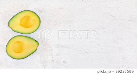 Two avocado halves with bright yellow pulp on white stone desk, view from above - wide banner space 59255599