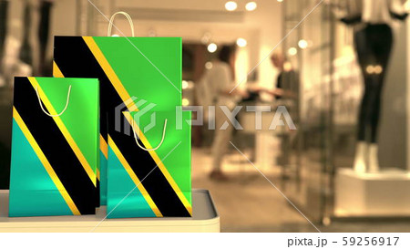 Flag of Tanzania on the paper shopping bags against blurred store entrance. Retail related 3D Flag of Tanzania on the paper shopping bags against blurred store entrance. Retail related 3D 59256917