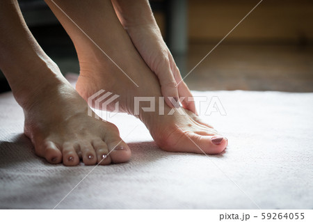 Closeup: Bare feet of woman, she massaging to release pain after long day wearing pointy and narrow shoes  -  Medical condition called bunions (Hallux valgus) Woman health concept - feet problem. 59264055