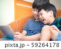 Smart looking asian preteen boy and his adorable little brother laughing together, watch funny cartoon on tablet with joy. Happy Brotherhood Moment, Children with Digital Entertainment, Gamification. 59264178