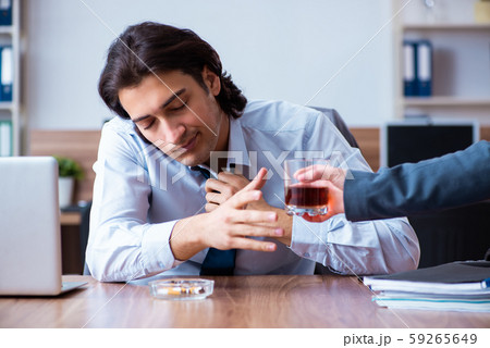 Male employee drinking alcohol and smoking cigarettes at workpla 59265649