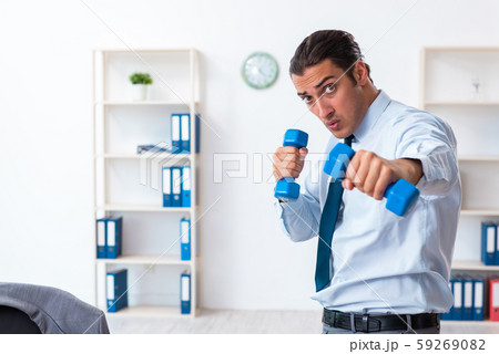 Young handsome employee doing sport exercises at workplace Young handsome employee doing sport exercises at workplace 59269082