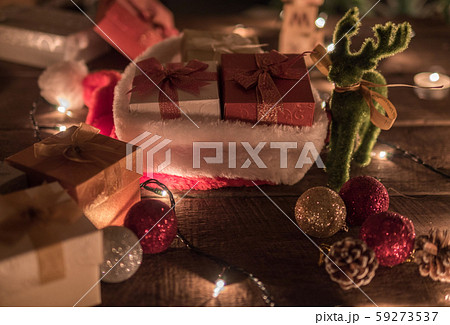 Christmas background with christmas ball, gift boxes, Santa hat, Reindeer and Christmas lights on a wooden background Christmas background with christmas ball, gift boxes, Santa hat, Reindeer and Christmas lights on a wooden background 59273537