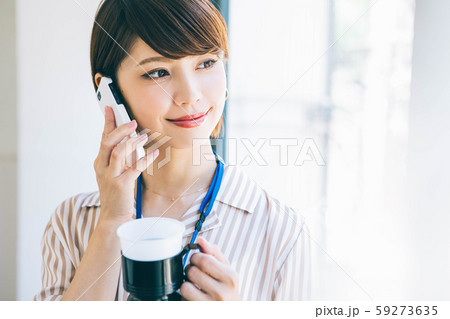 仕事中にコーヒーを飲みながら電話をする女性 仕事中にコーヒーを飲みながら電話をする女性 59273635