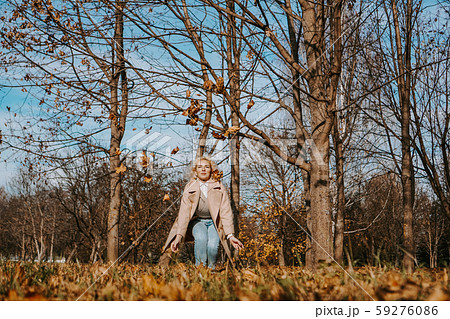 Happy woman in autumn park drop up leaves Happy woman in autumn park drop up leaves 59276086