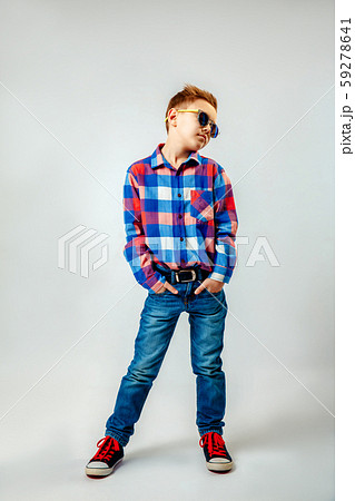Boy wearing colorful plaid shirt, blue jeans, gumshoes, sunglasses, posing and having fun in the Boy wearing colorful plaid shirt, blue jeans, gumshoes, sunglasses, posing and having fun in the 59278641