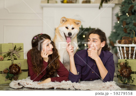 Young happy couple cuddling adorable akita inu dog Young happy couple cuddling adorable akita inu dog 59279558