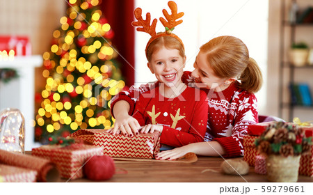 Happy family mother and child pack Christmas gifts at home near