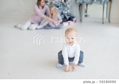 Portrait of cute adorable little blond toddler boy squatting in cozy living room and mother with Portrait of cute adorable little blond toddler boy squatting in cozy living room and mother with 59280090