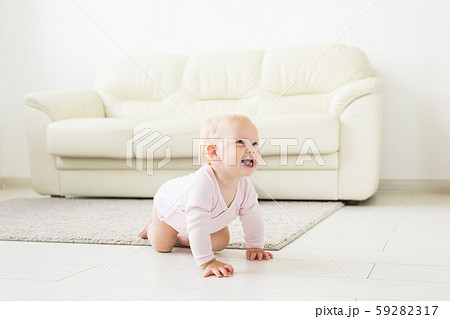 Portrait of a cute baby crawling and laughing on the floor at home Portrait of a cute baby crawling and laughing on the floor at home 59282317