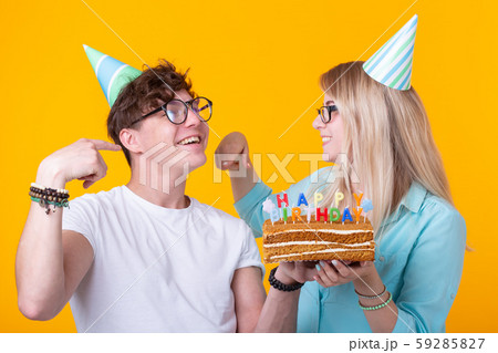 Cheerful young couple charming guy and cute girl in paper hats make foolish face and hold in their 59285827
