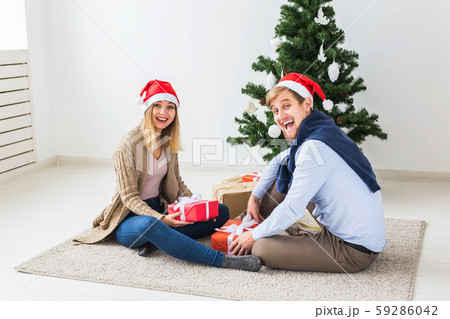 Holidays concept - Sweet couple opening Christmas gifts, sitting in the living room 59286042
