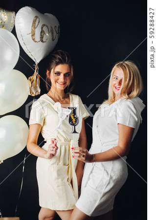 Two young ladies holding accessories and posing at 59288427