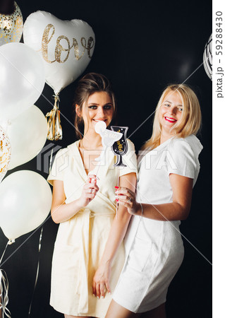 Two young ladies holding accessories and posing at Two young ladies holding accessories and posing at 59288430