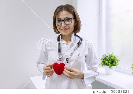 Female doctor with stethoscope holding heart, background hospital window 59288822