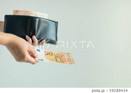 A hand picking a banknote from the short wallet and paying in EURO currency. 59289434