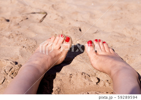 Feet of woman with nails painted red on the sand 59289594