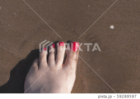 Feet of woman with nails painted red on the sand 59289597