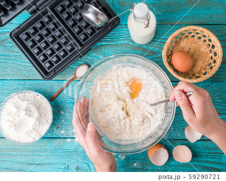 Making waffles at home - waffle iron, batter in bowl and ingredients - milk, eggs and flour. 59290721