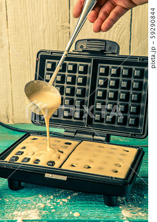 Making wafers at home. Pouring the dough into the waffle iron 59290844