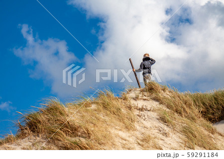 Young boy with stick standing on top of sand dune Young boy with stick standing on top of sand dune 59291184