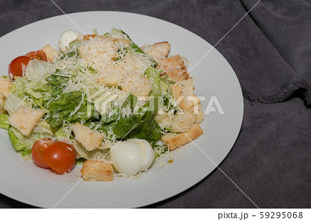 Caesar salad on a white plate and a dark 59295068