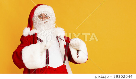 Funny Santa showing his Christmas suspenders over orange 59302644