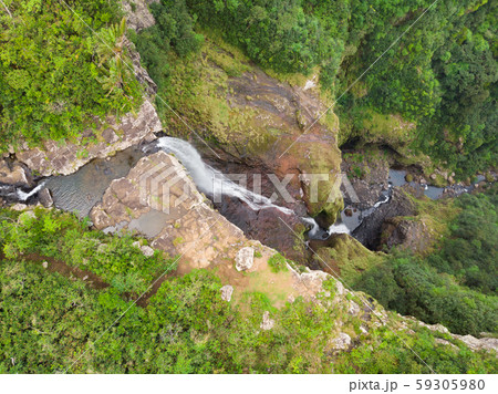 Aerial top view of travel couple waving to drone, standing on the edge of 500 feet waterfall in the Aerial top view of travel couple waving to drone, standing on the edge of 500 feet waterfall in the 59305980