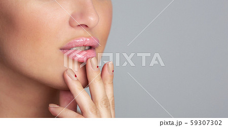 Lips care. Girl applying balm over grey background, closeup 59307302