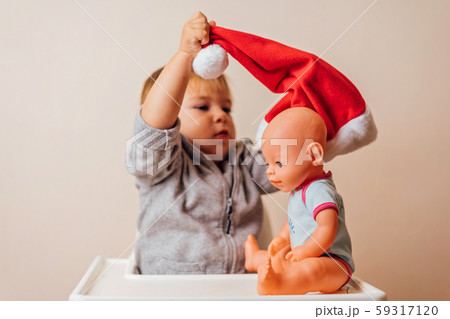 baby in Christmas bonnet dressing up the doll , on white background. copy space 59317120