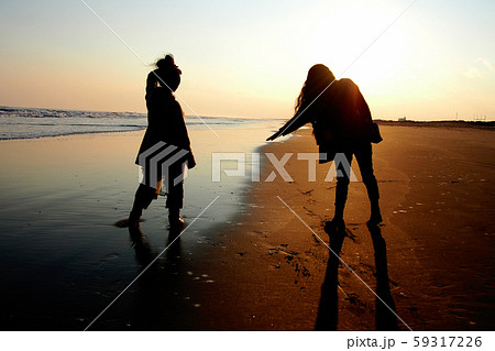 夕暮れの海辺に立つ女性二人 59317226