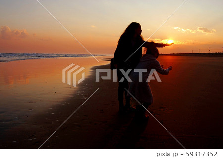 太陽を受け止める女性と、落とさないように拾おうとする女性 59317352