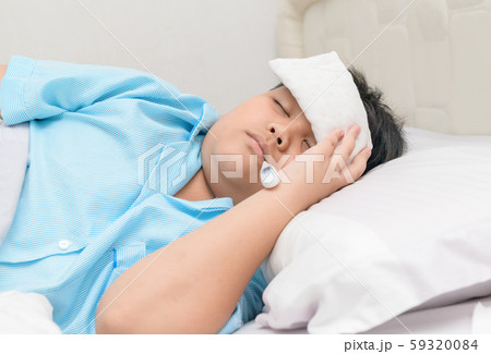 Sick boy with thermometer in mouth and compress on Sick boy with thermometer in mouth and compress on 59320084