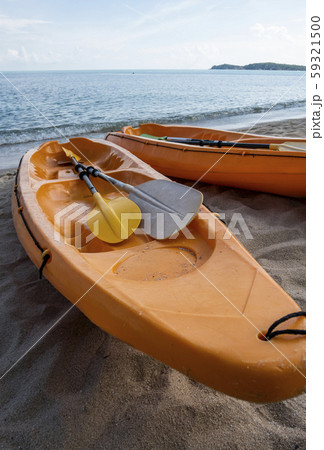 Two colorful orange kayaks on a sandy beach ready for paddlers in sunny day. Several orange Two colorful orange kayaks on a sandy beach ready for paddlers in sunny day. Several orange 59321500