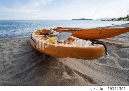 Two colorful orange kayaks on a sandy beach ready for paddlers in sunny day. Several orange 59321505