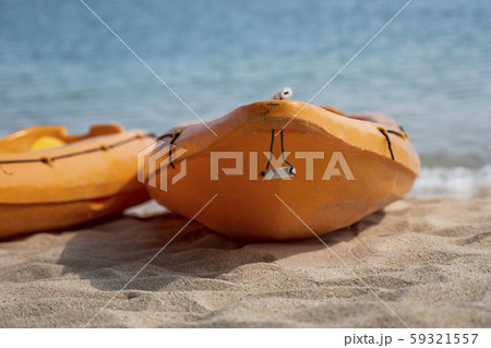 Two colorful orange kayaks on a sandy beach ready for paddlers in sunny day. Several orange Two colorful orange kayaks on a sandy beach ready for paddlers in sunny day. Several orange 59321557