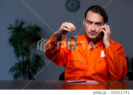 Young convict man sitting in dark room 59321741