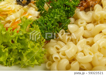 Boiled macaroni on a white plate with fresh herbs. Boiled macaroni on a white plate with fresh herbs. 59323521