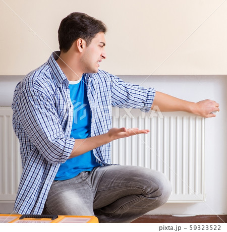 Young repairman contractor repairing heating panel Young repairman contractor repairing heating panel 59323522