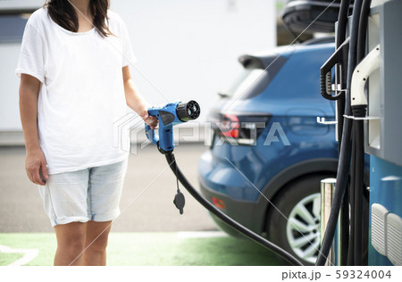 Woman charge Electric car on gas station. Blue car Woman charge Electric car on gas station. Blue car 59324004
