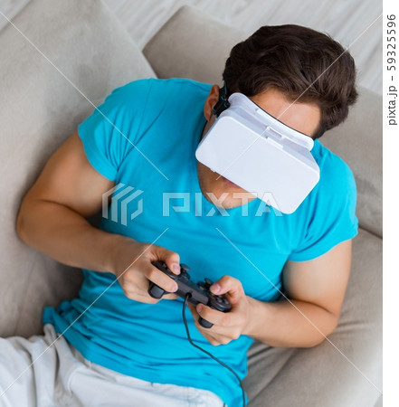 Young man wearing VR glasses relaxing on couch sofa Young man wearing VR glasses relaxing on couch sofa 59325596