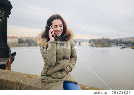 Smiling tourist woman in Prague speaking on smartphone. Young woman tourist stands on the Charles 59328827