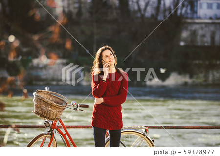 A young female traveler enjoying stands next to a bicycle near a river in the city of Basel 59328977