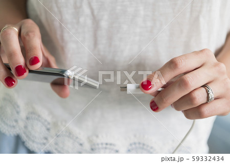 Woman plugging charger into smart phone Woman plugging charger into smart phone 59332434