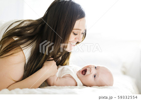 Smiling mother lying with her son on bed Smiling mother lying with her son on bed 59332554
