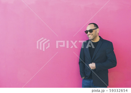 Smiling man wearing sunglasses and blazer by pink wall 59332654