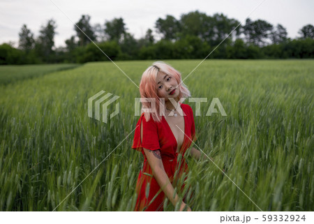 Woman with pink hair wearing red dress in wheat field 59332924