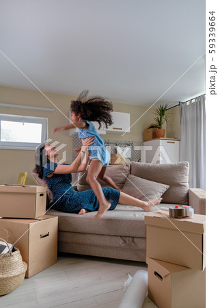 Mom and daughter multiraces move to a new apartment. Have fun jumping and playing on sofa. 59339664